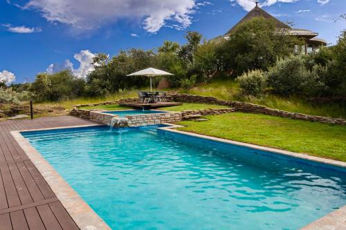 a swimming pool with a table and an umbrella at Naankuse Lodge in Windhoek