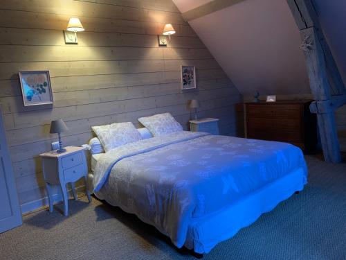 a bedroom with a blue bed and a wooden wall at Le Clos des ifs in Thiétreville