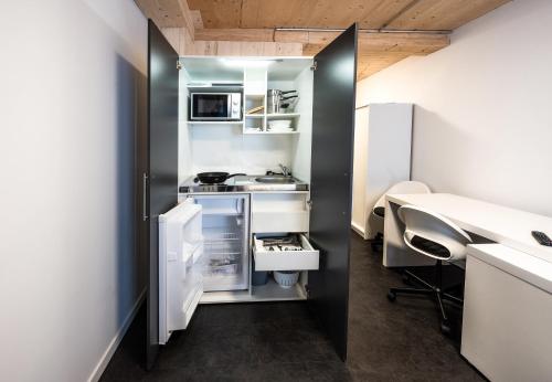 una pequeña cocina con electrodomésticos blancos y escritorio. en Boardinghouse-Landau en Landau in der Pfalz