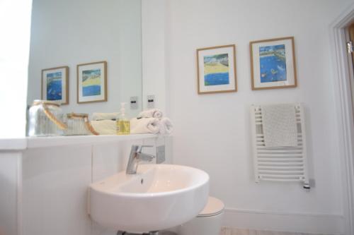 Baño blanco con lavabo y algunas fotos en la pared en Beautiful flat in luxury Graylingwell development en Chichester