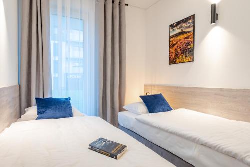 twee bedden in een hotelkamer met een boek op het bed bij Apartament Blue Moon in Jelenia Góra