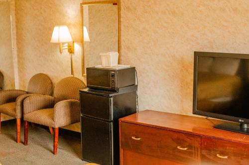 a hotel room with a flat screen tv and chairs at Colfax Inn By Marifah in Colfax