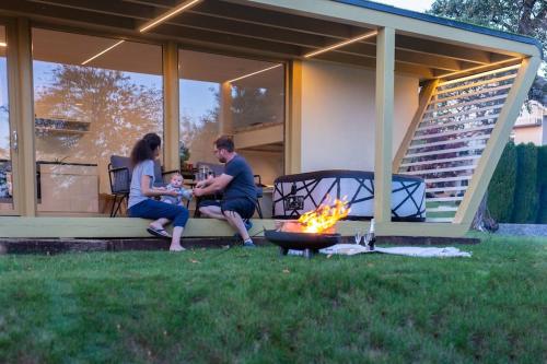 Ein Mann und eine Frau sitzen auf einer Veranda neben einem Feuer in der Unterkunft Holiday house Hona Lux in Velike Lašče