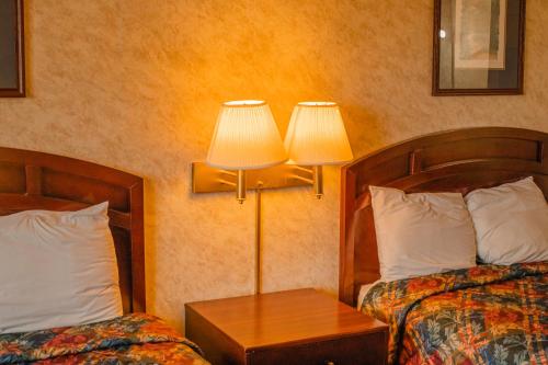 a hotel room with two beds and a table with two lamps at Colfax Inn By Marifah in Colfax