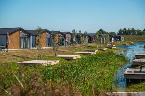 a row of houses next to a river with benches at EuroParcs De IJssel Eilanden in Kampen