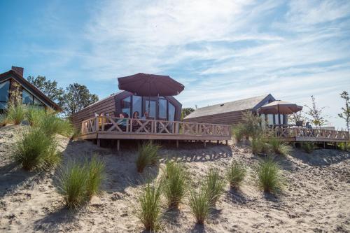 a wooden house on the beach with an umbrella at EuroParcs De IJssel Eilanden in Kampen