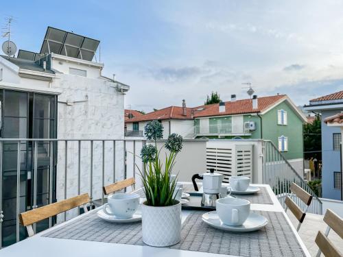 einen Tisch mit Tassen und Untertassen auf einem Balkon in der Unterkunft Homiday - Residenza Caravelle in Pineto