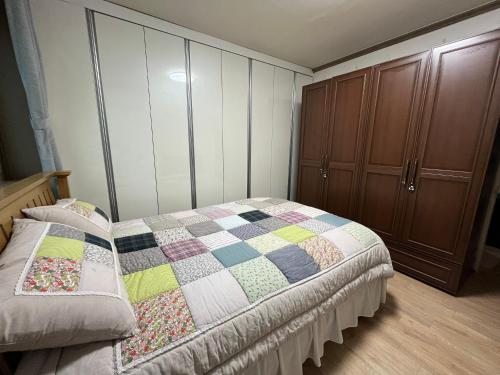 a bedroom with a bed with a quilt on it at Gangneung Mediterranean Pension in Gangneung