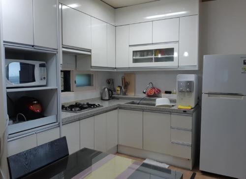 a kitchen with white cabinets and a white refrigerator at Gangneung Mediterranean Pension in Gangneung