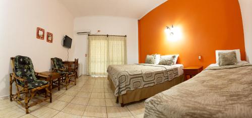 a hotel room with two beds and a table and chairs at Palo Rosa Lodge in Puerto Iguazú