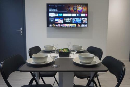 a black table with chairs and plates and wine glasses at Cosy T2 Wifi Parking Proche gare CENTRE VILLE in Saint-Quentin