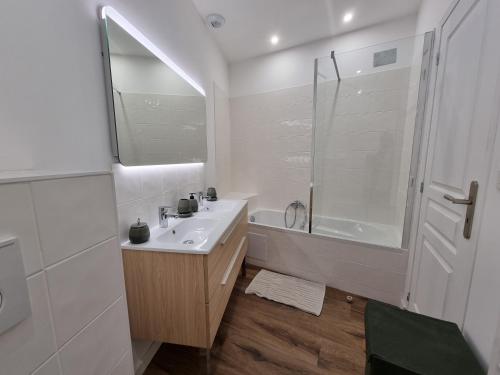 een witte badkamer met een wastafel en een douche bij HOME ET HOLIDAY Le Petit Verdot in Viviers