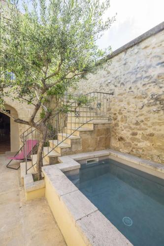 - une piscine avec un arbre à côté d'un bâtiment dans l'établissement La Petite Baronne, à Saint-Hilaire-dʼOzilhan