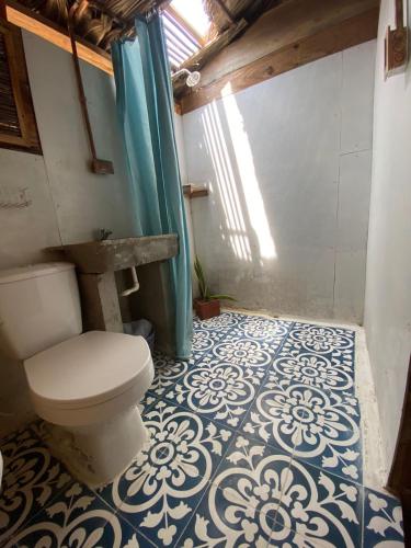 a bathroom with a toilet and a blue and white floor at Playa Jaguar - Beach Club in Moñitos