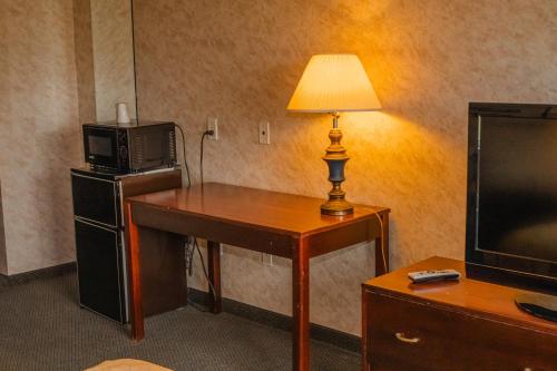 a room with a desk with a microwave and a television at Colfax Inn By Marifah in Colfax