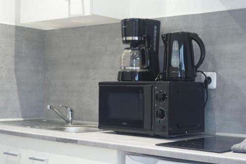 - un comptoir de cuisine avec une cafetière et un four micro-ondes dans l'établissement Coquet STUDIO TOUT ÉQUIPÉ CENTRE VILLE WIFI 2PERS, à Saint-Quentin
