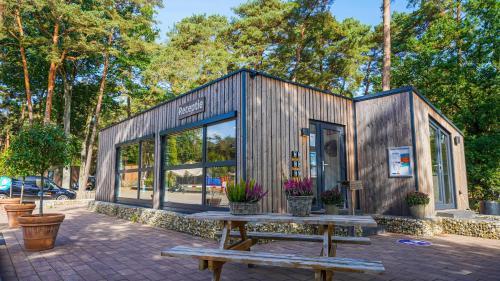 a small wooden building with a picnic table and benches at EuroParcs Hoge Kempen in Zutendaal