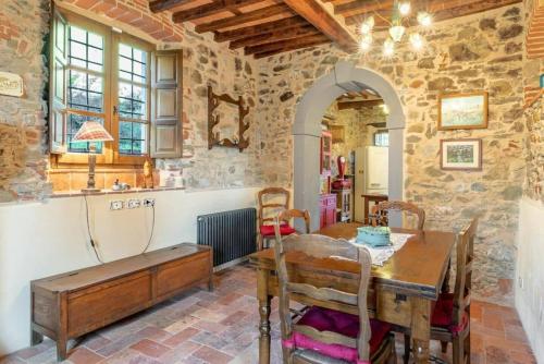 een keuken met een houten tafel in een kamer met stenen muren bij Villa Pera by Nicola Real Estate in Corsanico-Bargecchia