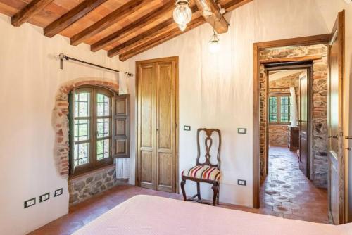 een slaapkamer in een huis met een stoel op de gang bij Villa Pera by Nicola Real Estate in Corsanico-Bargecchia