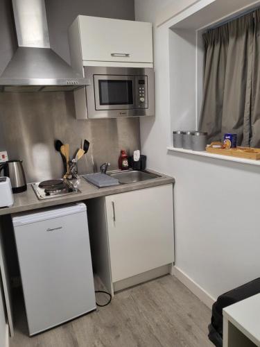 a small kitchen with a sink and a microwave at Theatre House Apartment 13 in Coventry