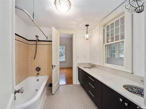 a bathroom with a tub and a sink and a bath tub at The Gator Manor – 6 Bedrooms Walk to UF / Stadium in Gainesville