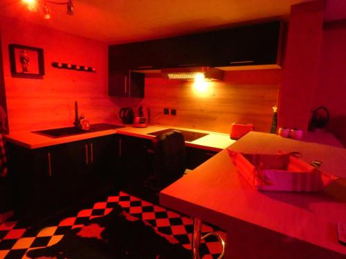 a kitchen with red lighting and a table and a sink at LOVE ROOM Le rouge et noir in Barr