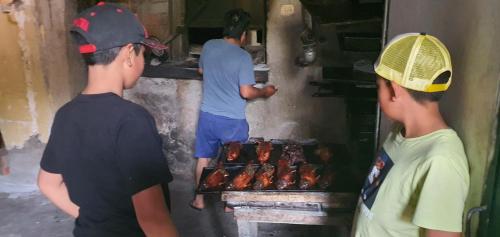 three men are standing around a grill with hot dogs at Casona Mollepata in Mollepata