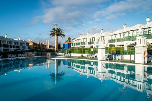 een zwembad met water voor sommige gebouwen bij Acogedor bungalow muy luminoso in Maspalomas