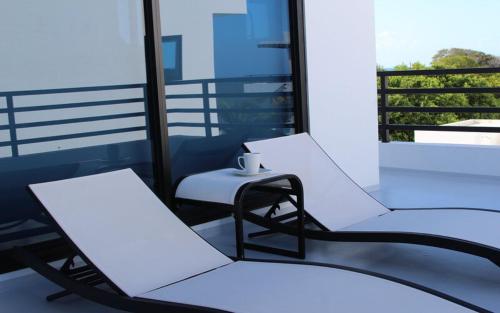 Duas cadeiras brancas e uma mesa numa varanda em Blu Zen em Caye Caulker