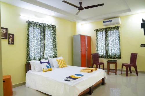 a bedroom with a bed with chairs and curtains at Hotel Yellow Bells in Hyderabad