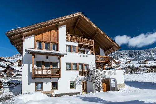 a house with a balcony in the snow at Apartments Tino in La Valle