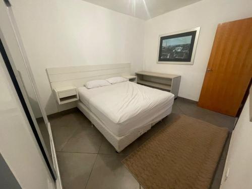 a small bedroom with a white bed and two tables at Cristal casa de vidro in São Thomé das Letras