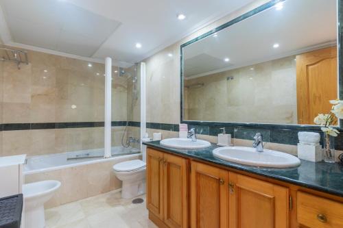 a bathroom with two sinks and a tub and a toilet at Deluxe Apartment on the First Line in Marbella