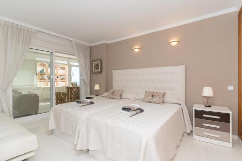 a white bedroom with a large bed and a window at Deluxe Apartment on the First Line in Marbella