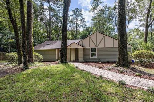 a house in the woods with trees in front of it at Gator Pool and Hot Tub House -1.5 miles to Stadium in Gainesville