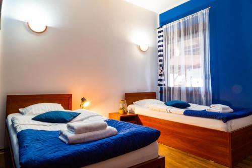 two beds in a room with blue walls at Hotel Nenufar in Kościan