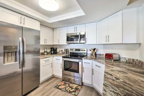 a kitchen with white cabinets and a stainless steel refrigerator at Waterfront Port Richey House with Heated Pool! in Port Richey