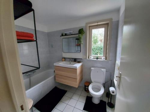 a bathroom with a toilet and a sink and a window at The Beach House in Middelkerke