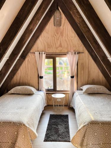 a attic bedroom with two beds and a window at CABAÑA PARCELA VISTA HERMOSA in Puerto Aisén
