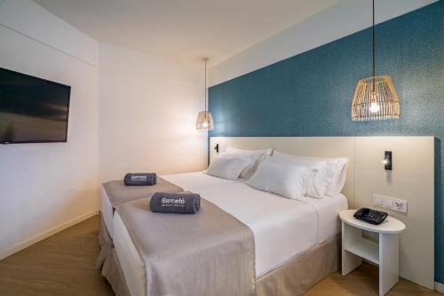 a bedroom with a large white bed and a table at Barceló Fuerteventura Royal Level in Caleta De Fuste