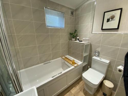 a bathroom with a tub and a toilet and a sink at Holicarrs - Gingerlily in Riccall