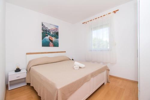 - une chambre blanche avec un lit et une fenêtre dans l'établissement Apartment Sokol, à Batalaži