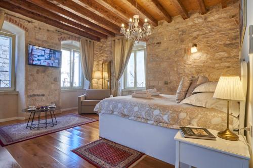 a bedroom with a large bed and a stone wall at Villa Split Heritage Hotel in Split