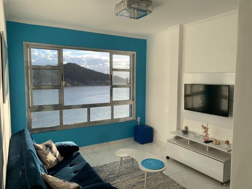 uma sala de estar com um sofá e uma grande janela em Cobertura Pé na Areia e Incrível Vista Para a Praia em São Vicente