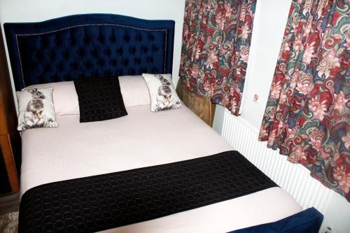 a bedroom with a bed with a black headboard and curtains at Central London rooms in London