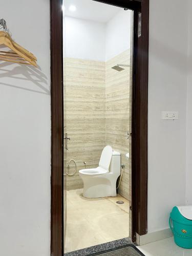 a bathroom with a toilet and a glass door at Radha Krishna Bhawan, Homestay in Vrindāvan