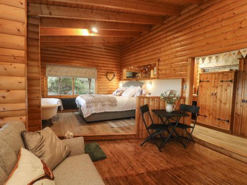 Dormitorio en cabaña de madera con cama y escritorio en Whitemoor Lodge, en Barnoldswick