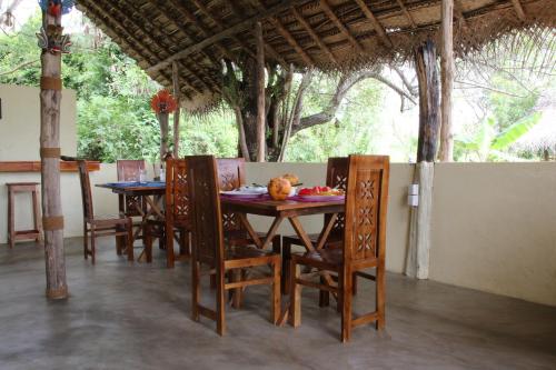 einen Holztisch und Stühle in einem Zimmer mit Bäumen in der Unterkunft Nirvaan Safari Lodge in Wilpattu Nationalpark