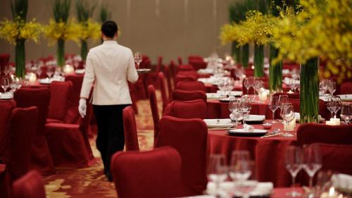 a person walking through a banquet hall with red tables at InterContinental Suzhou Hotel by IHG in Suzhou