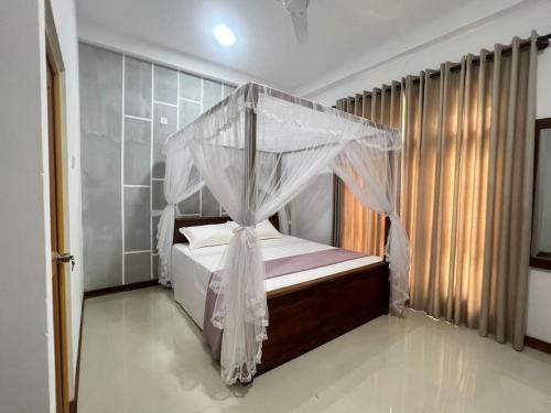 a bedroom with a bed with a mosquito net at Plantation Inn in Weligama
